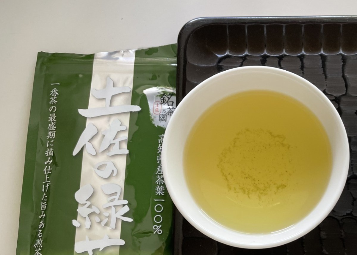 高知県の煎茶「土佐の緑茶」のパッケージと、黄色みの強い水色の湯呑