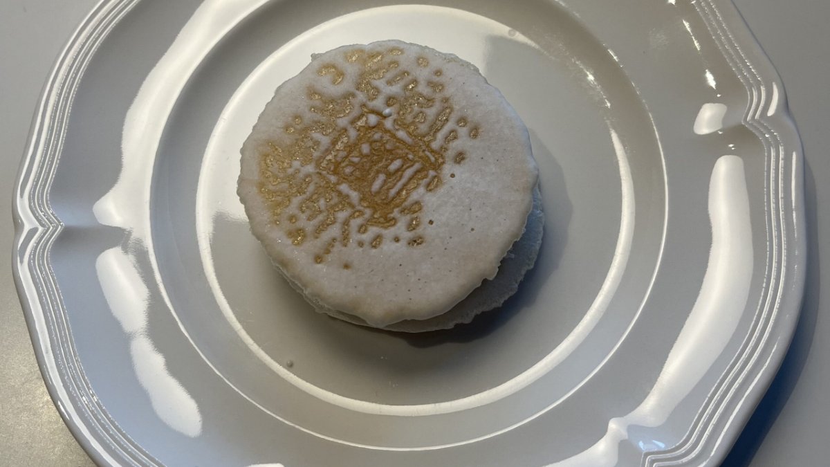 白い皿にのせた夢二の宵待草。丸い麩焼き煎餅の表面に金色の焼き模様が入っている