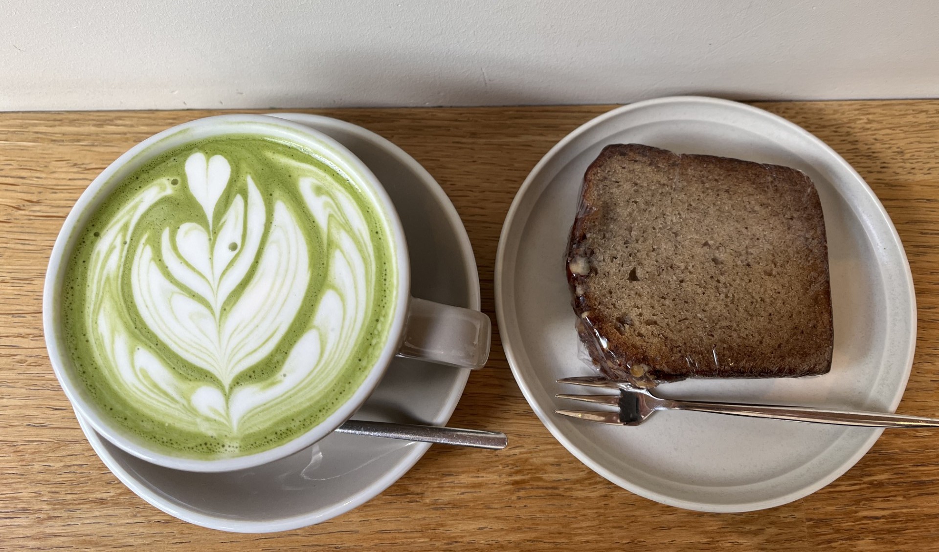 アムステルダムのカフェで頼んだ抹茶ラテとバナナケーキ。淡い黄緑色の抹茶ラテにリーフのラテアートが描かれている
