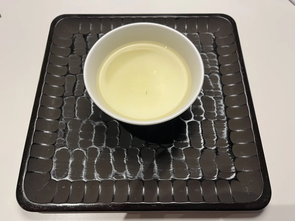 一煎目の水色。白い湯呑に注いだ淡い黄緑色の煎茶
